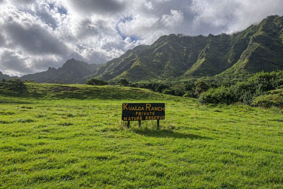 Kualoa Ranch Private Nature Reserve sign with lush green valley and Koʻolau mountains during a tour with our Kualoa Ranch Tours agency